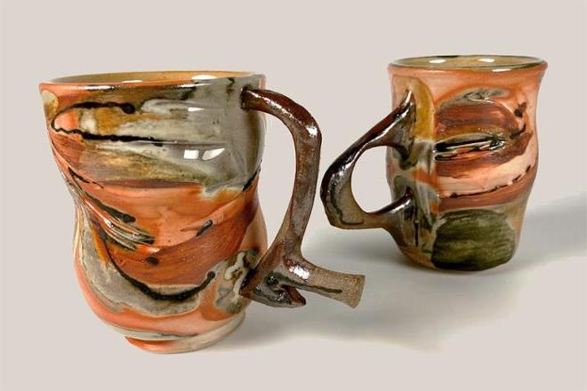 Two ceramic mugs with striking orange flashing and contrasting glossy grey glaze made from baking soda. The handles are made from a darker clay than the porcelain cup and are inspired by line drawings of my long-time friend (Eleda). 