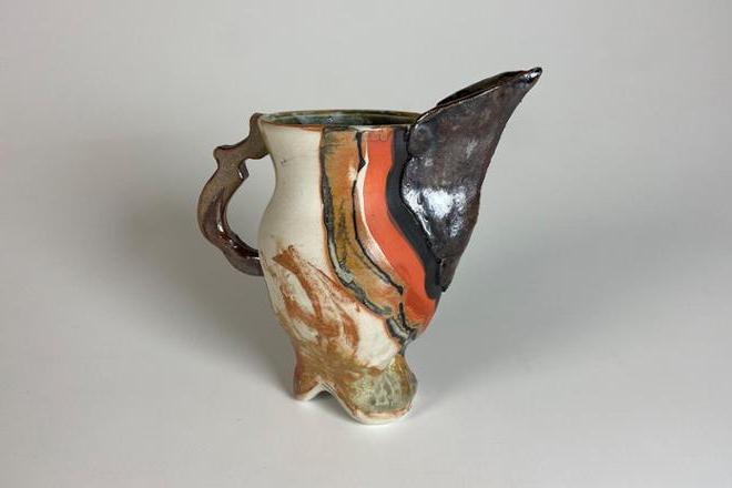 Ceramic pitcher with bird-like spout made with a combination of dark stoneware and porcelain and finished with a baking soda glaze that flashes the surface orange. Black and orange underglaze were also added to emphasize the form.