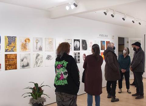 gallery staff talking to a crowd of viewers at an exhibit in the Cohen gallery