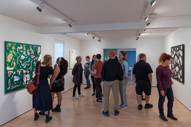 group of people viewing all the artwork on display